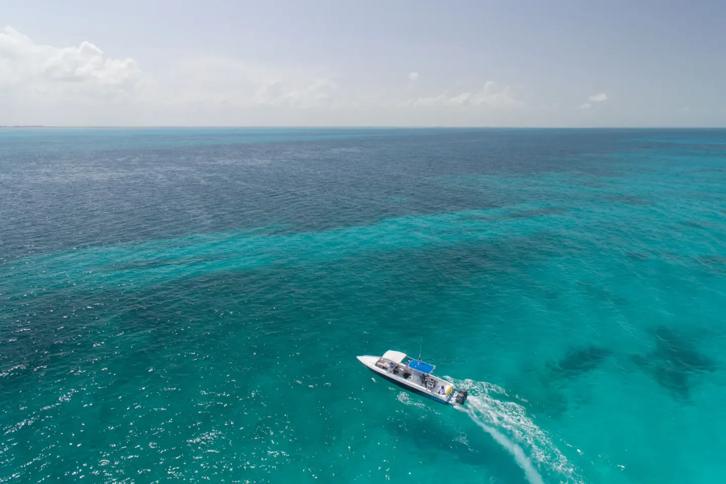 Boat crossing bright turquoise water near Privilege Aluxes Isla Mujeres.