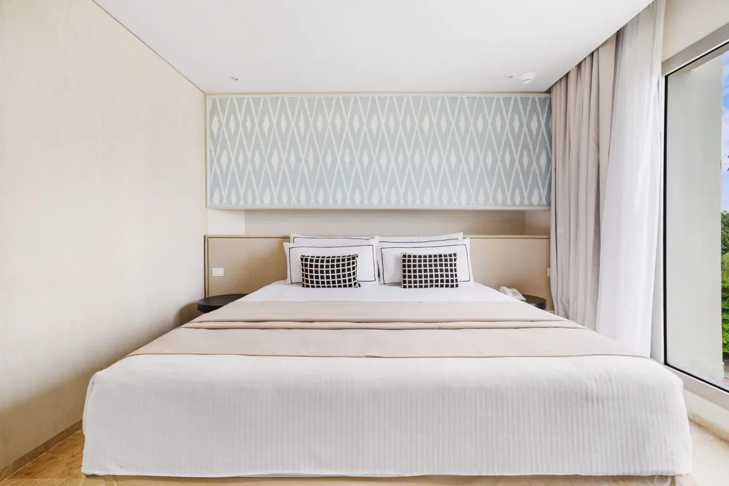 Aluxes Room king bed with white linens and patterned headboard at Privilege Aluxes Isla Mujeres.