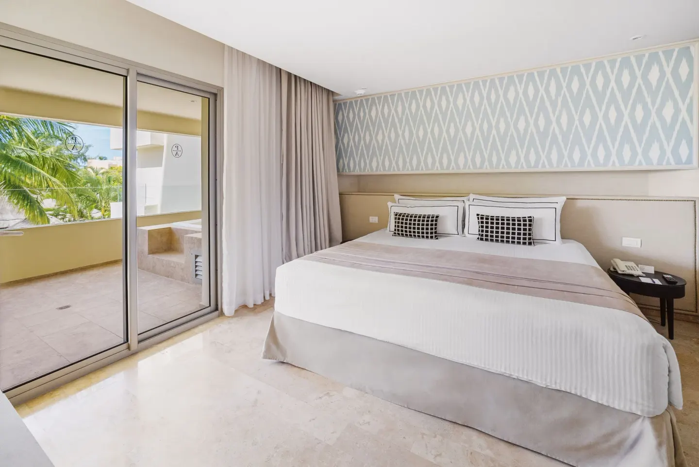 Premium Suite king bed beside sliding doors to the terrace at Privilege Aluxes Isla Mujeres.