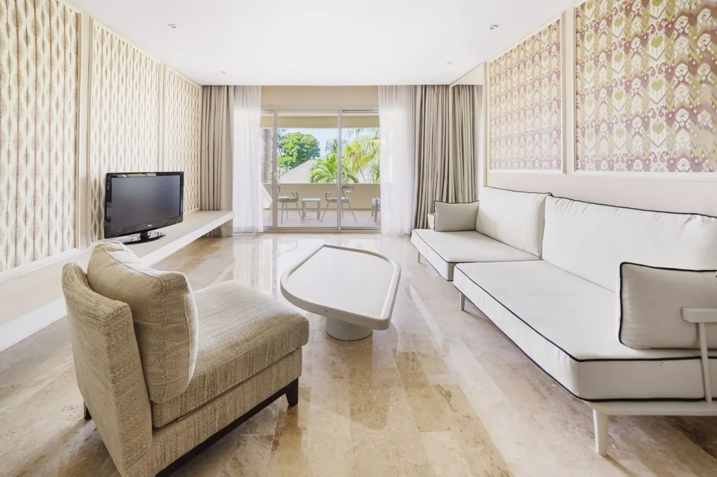Premium Suite living room with sofa, lounge chair, and balcony view at Privilege Aluxes Isla Mujeres.