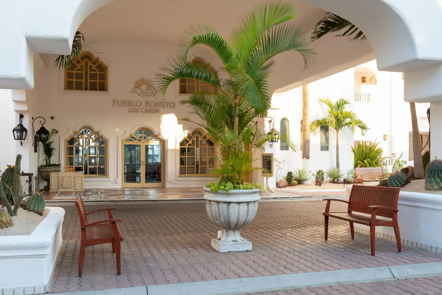 Arched courtyard entrance with palms and benches at Pueblo Bonito Los Cabos Blanco.