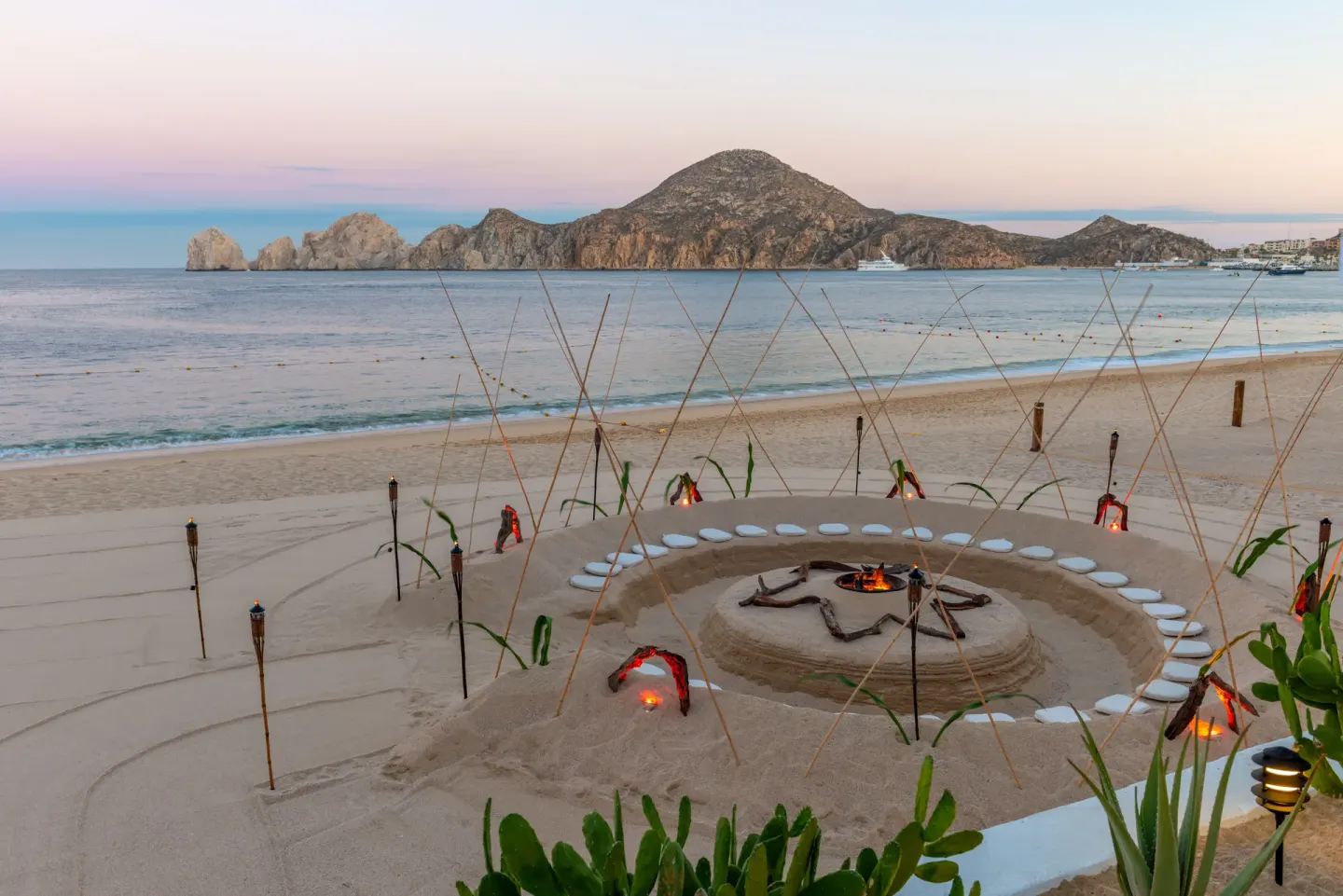 Beach fire-pit seating faces the bay and rock formations at Pueblo Bonito Los Cabos Blanco.
