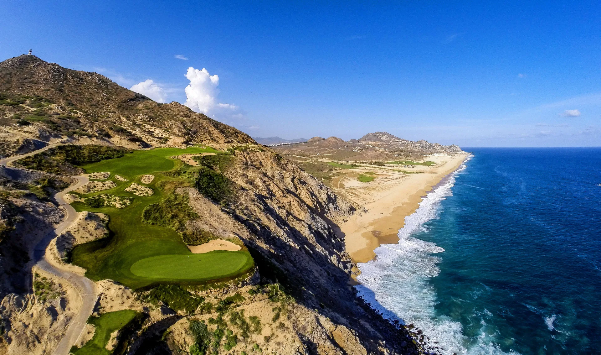 Coastal cliffs and ocean near Pueblo Bonito Los Cabos Blanco with green fairways on the hillside.