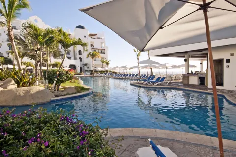 Curving pool with umbrellas, palms, and lounge chairs at Pueblo Bonito Los Cabos Blanco.