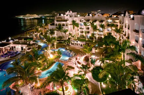 Night view of pools, palms, and illuminated buildings at Pueblo Bonito Los Cabos Blanco.