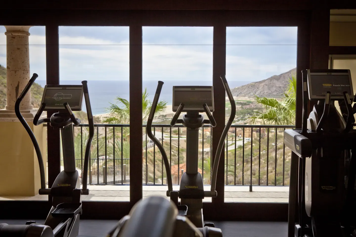 Elliptical machines facing ocean-view windows at Pueblo Bonito Montecristo Luxury Villas.