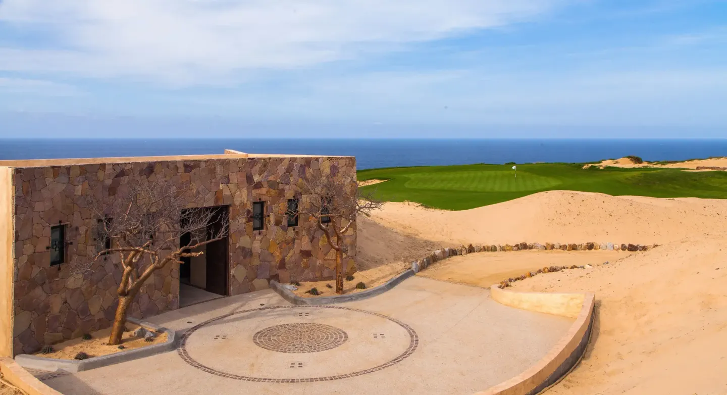 Stone golf building, dunes, and ocean at Pueblo Bonito Montecristo Luxury Villas.