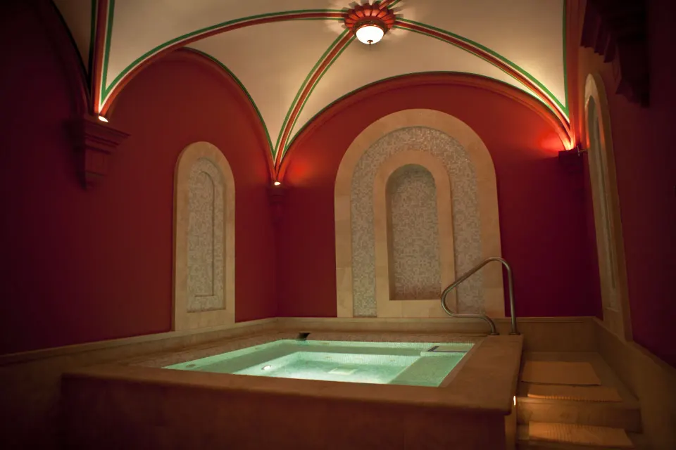 Indoor spa soaking pool with arched red walls at Pueblo Bonito Montecristo Luxury Villas.