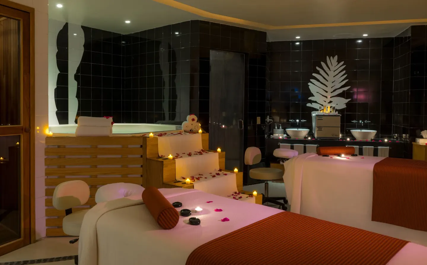 Candlelit spa treatment room with massage tables, soaking tub, and black tile walls at Pueblo Bonito Pacifica Golf & Spa Reso