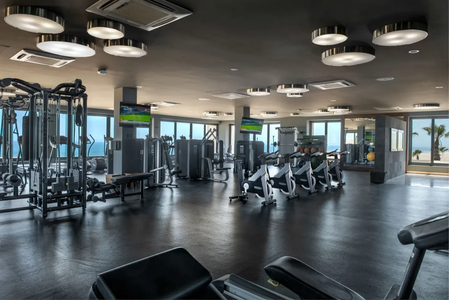 Fitness center with cardio machines, weight equipment, TVs, and ocean-facing windows at Pueblo Bonito Pacifica Golf & Spa Res