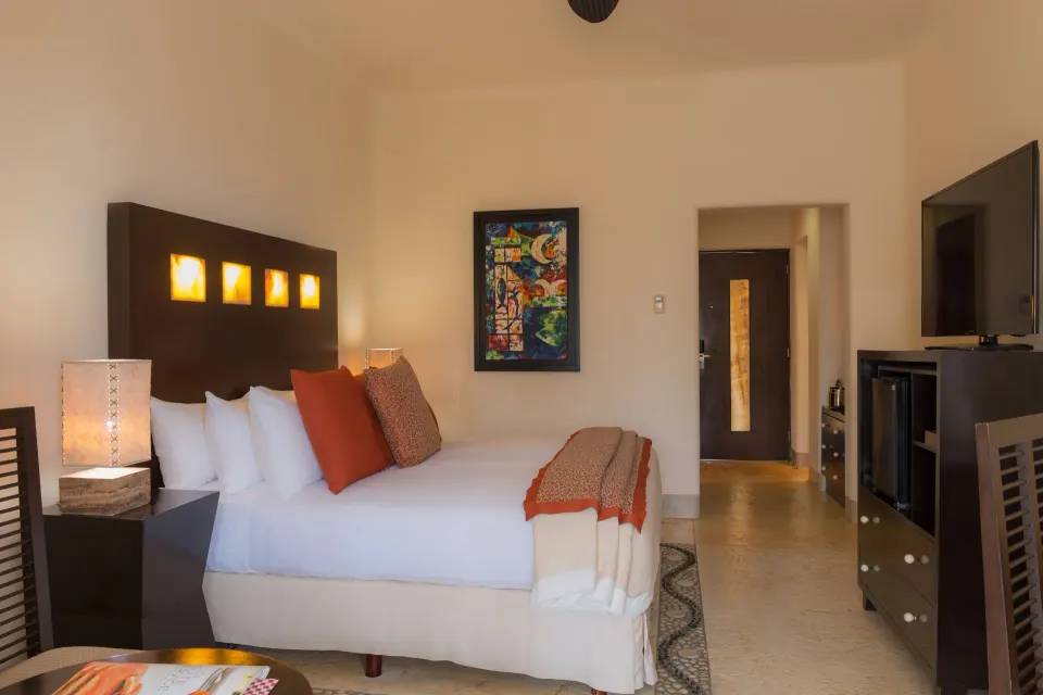 Deluxe Room king bed, TV cabinet, and entry at Pueblo Bonito Pacifica Golf & Spa Resort.