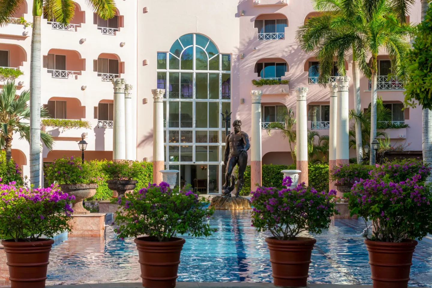Courtyard pool with statue and pink facade at Pueblo Bonito Rose Resort and Spa.