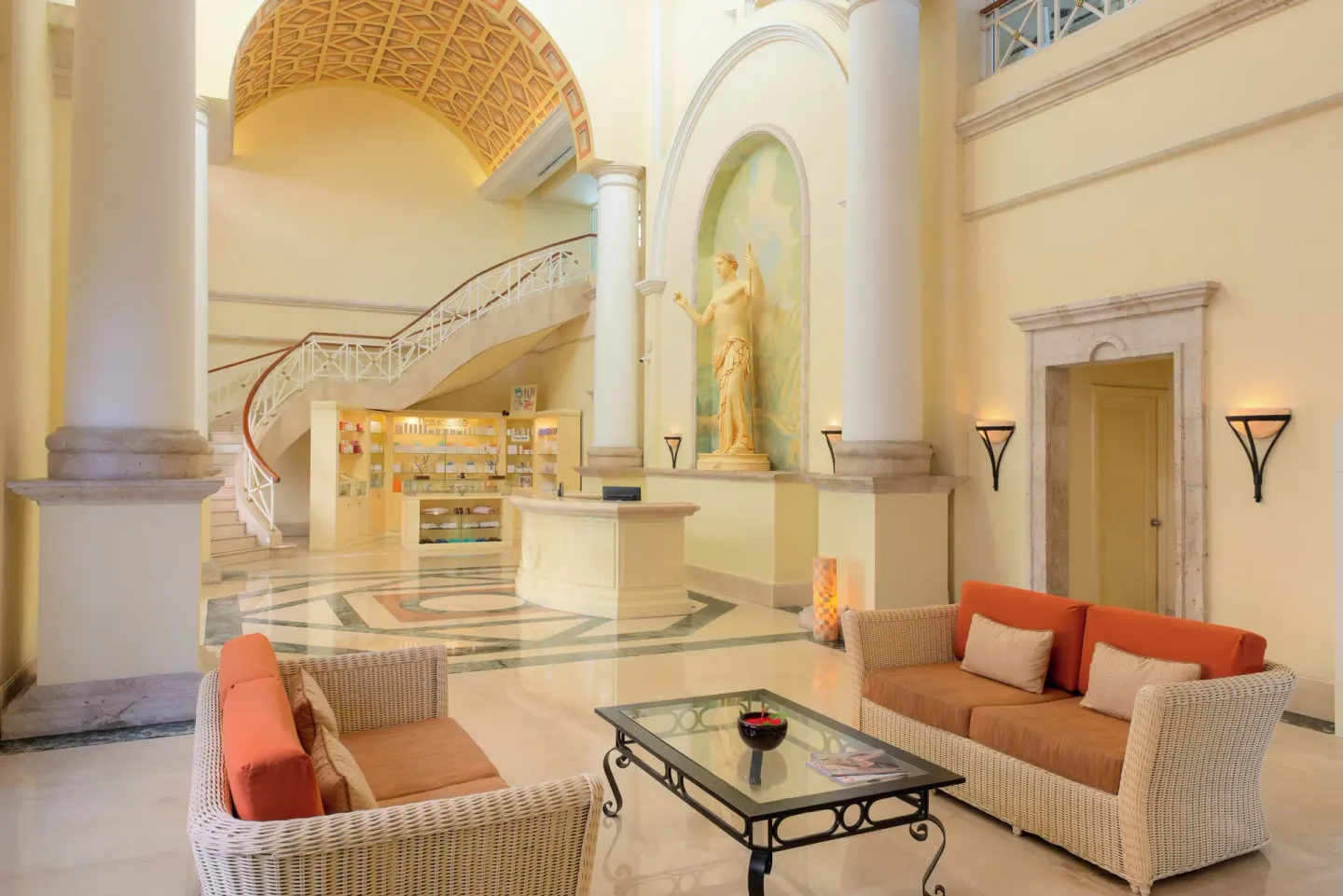 Lobby lounge with wicker seating and grand staircase at Pueblo Bonito Rose Resort and Spa.
