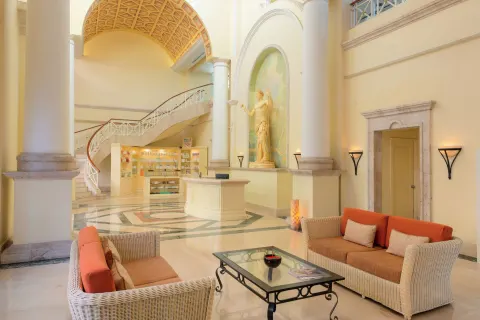 Lobby lounge with wicker seating and grand staircase at Pueblo Bonito Rose Resort and Spa.