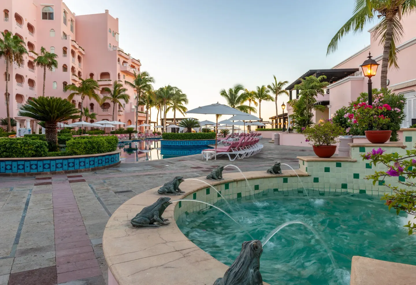 Frog fountain, pool terrace, palms, and pink resort buildings at Pueblo Bonito Rose Resort and Spa.