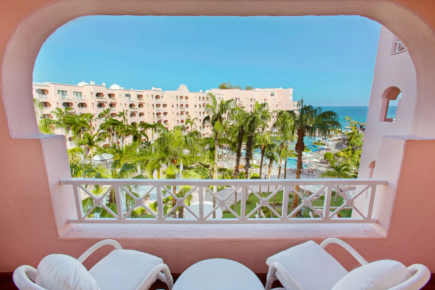 Junior Suite balcony overlooking palms, pool, and sea at Pueblo Bonito Rose Resort and Spa.