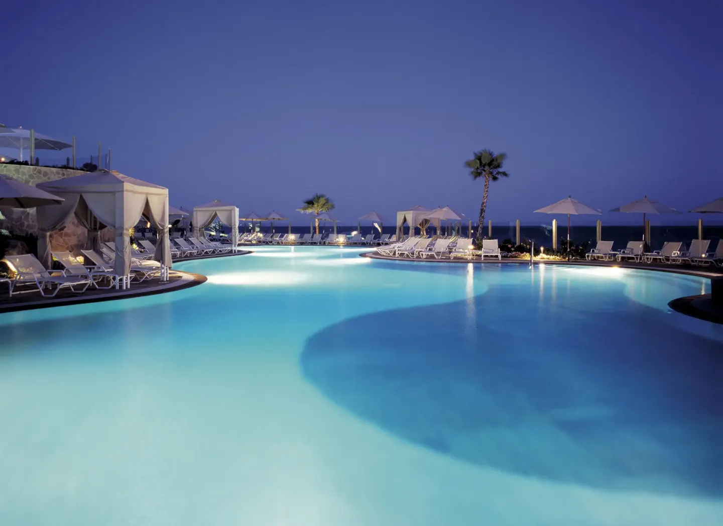 Evening pool with cabanas and lounge chairs at Pueblo Bonito Sunset Beach Golf & Spa Resort.