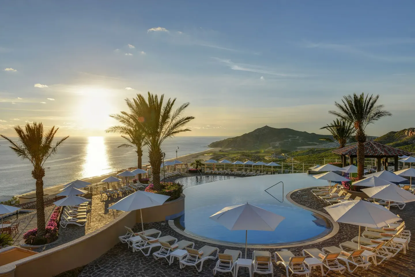 Sunlit hilltop pool with ocean and mountain views at Pueblo Bonito Sunset Beach Golf & Spa Resort.