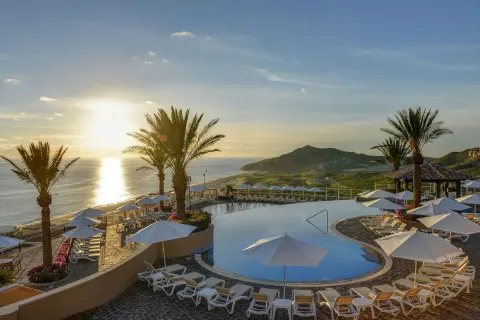 Sunlit hilltop pool with ocean and mountain views at Pueblo Bonito Sunset Beach Golf & Spa Resort.