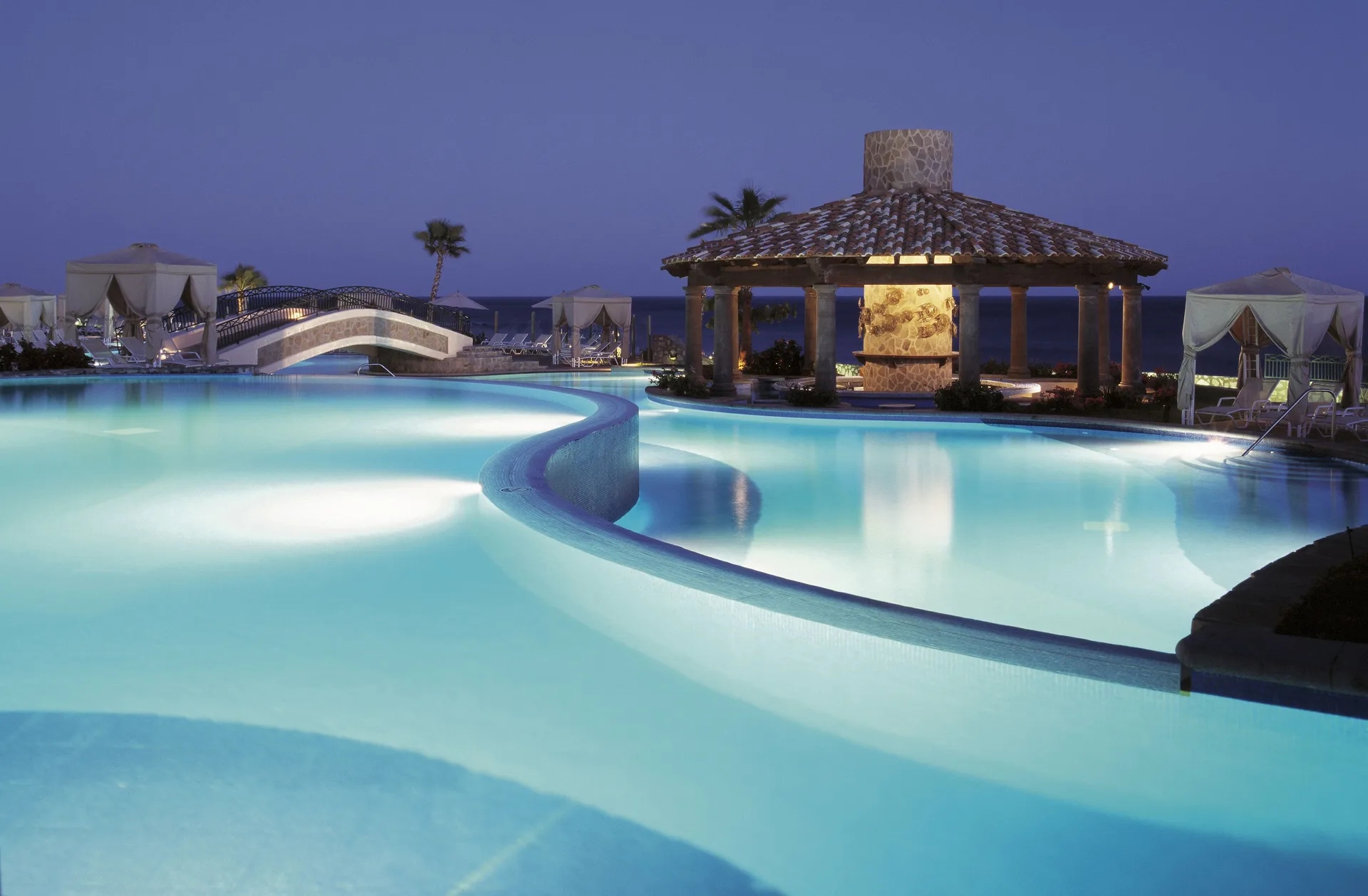 Illuminated pool and pavilion at dusk at Pueblo Bonito Sunset Beach Golf & Spa Resort.