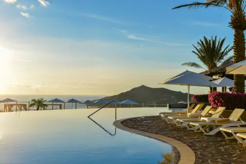 Infinity pool with lounge chairs and mountain view at Pueblo Bonito Sunset Beach Golf & Spa Resort.