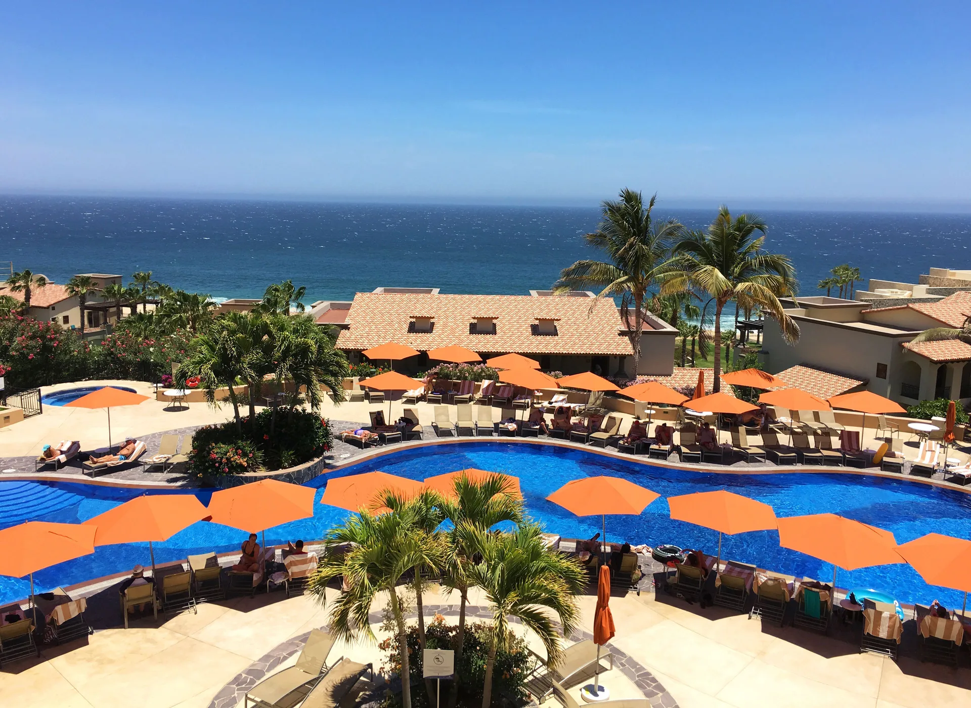 Oceanview pool with orange umbrellas at Pueblo Bonito Sunset Beach Golf & Spa Resort.