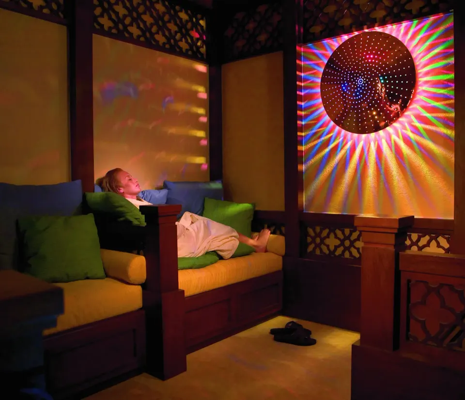 Spa lounge with a reclining guest and colorful light display at Pueblo Bonito Sunset Beach Golf & Spa Resort.