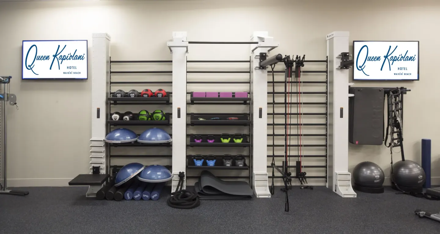 Fitness equipment is neatly organized on wall racks at Queen Kapiolani Hotel.