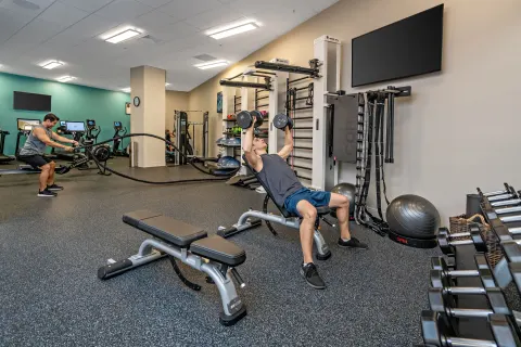 Guests use free weights and cardio equipment in the fitness center at Queen Kapiolani Hotel.