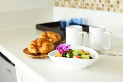 Fruit, croissants, and coffee mugs on a counter at Queen Kapiolani Hotel.