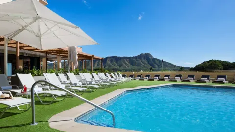 Pool with handrail, shaded loungers, and Diamond Head at Queen Kapiolani Hotel.