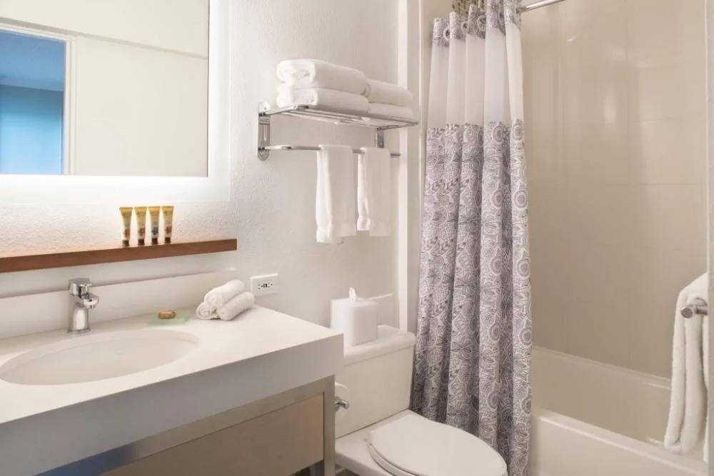 Diamond Head View Balcony bathroom with vanity, towels, and tub at Queen Kapiolani Hotel.