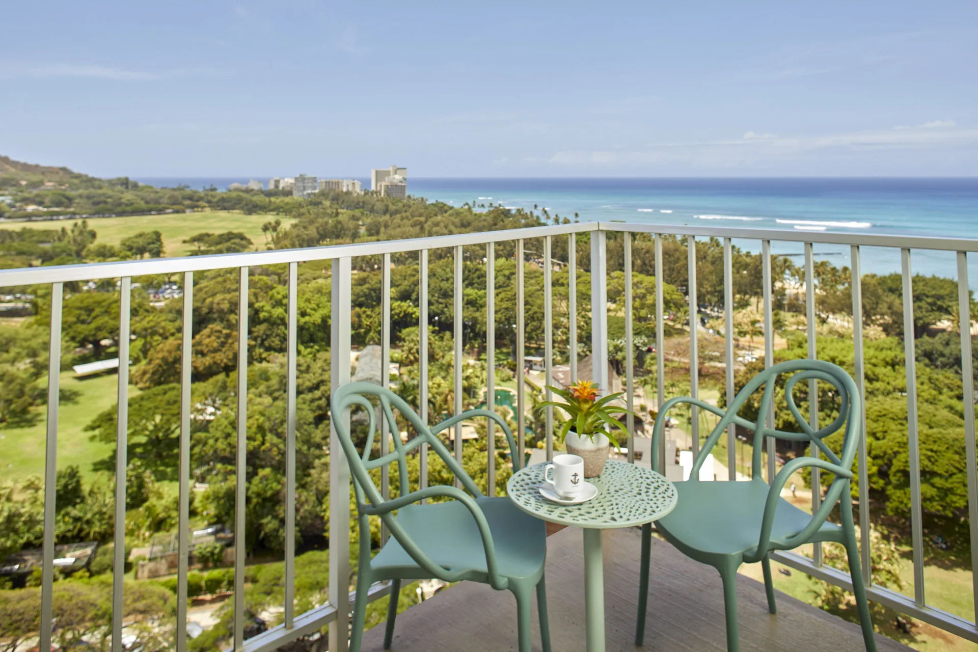 Junior Suite balcony seating with ocean and park views at Queen Kapiolani Hotel.