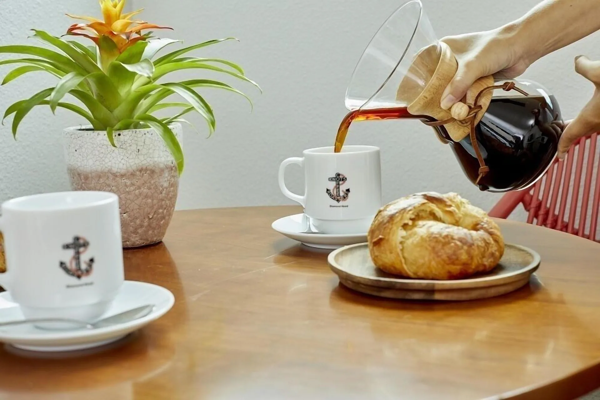 Junior Suite table with coffee, pastries, and a potted plant at Queen Kapiolani Hotel.
