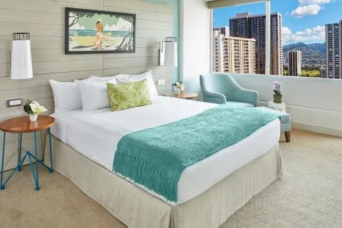 Penthouse One Bedroom City View Suite bed and city-facing window at Queen Kapiolani Hotel.