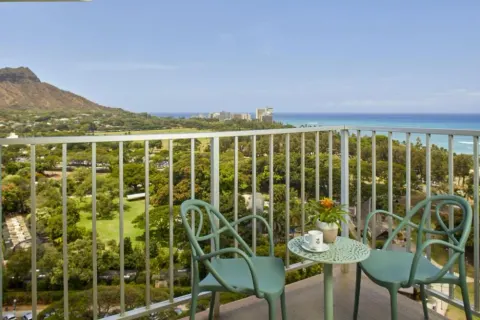 Penthouse One Bedroom Ocean View Suite balcony with chairs and ocean view at Queen Kapiolani Hotel.