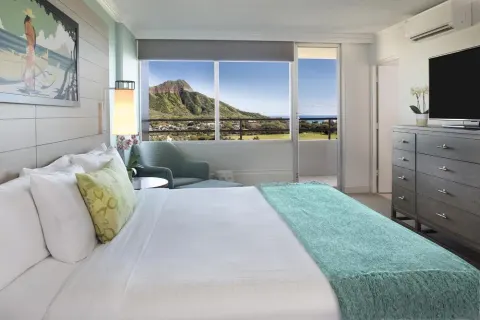 Penthouse One Bedroom Ocean View Suite bedroom with ocean and Diamond Head views at Queen Kapiolani Hotel.