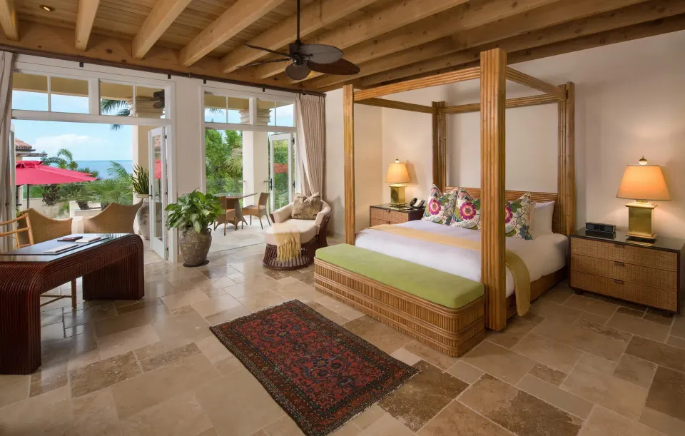 Spacious suite with four-poster king bed and terrace doors overlooking the sea at Quintessence Hotel