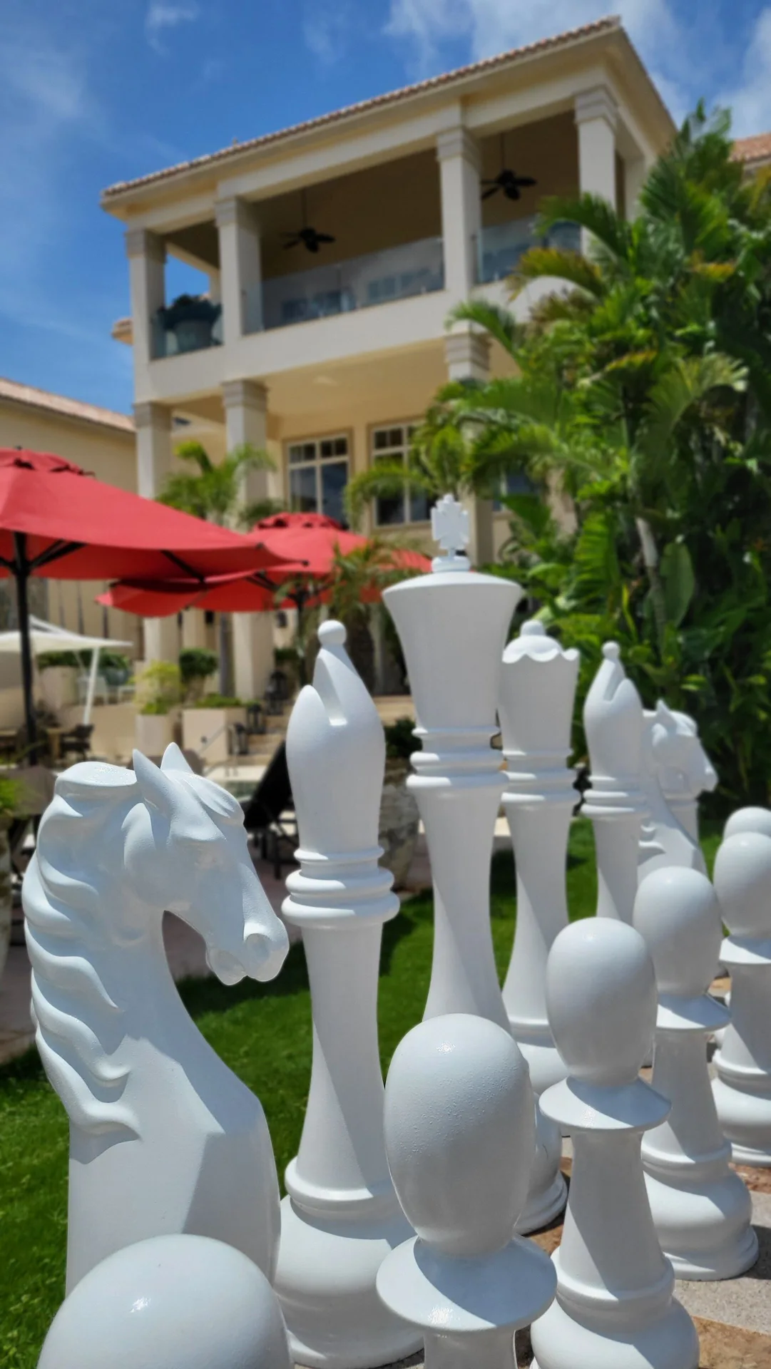 Oversized outdoor chess pieces on the lawn with the resort in the background at Quintessence Hotel