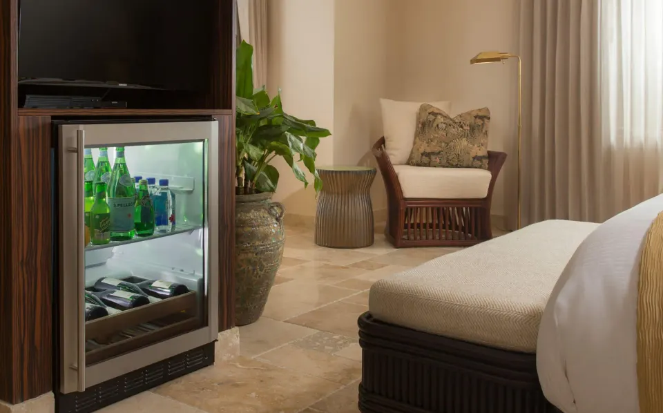 Guest room minibar and seating area with a view of the bed at Quintessence Hotel