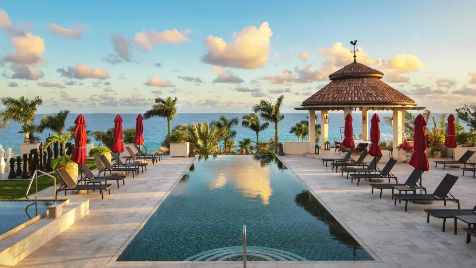 Infinity pool deck with loungers and ocean view at Quintessence Hotel.