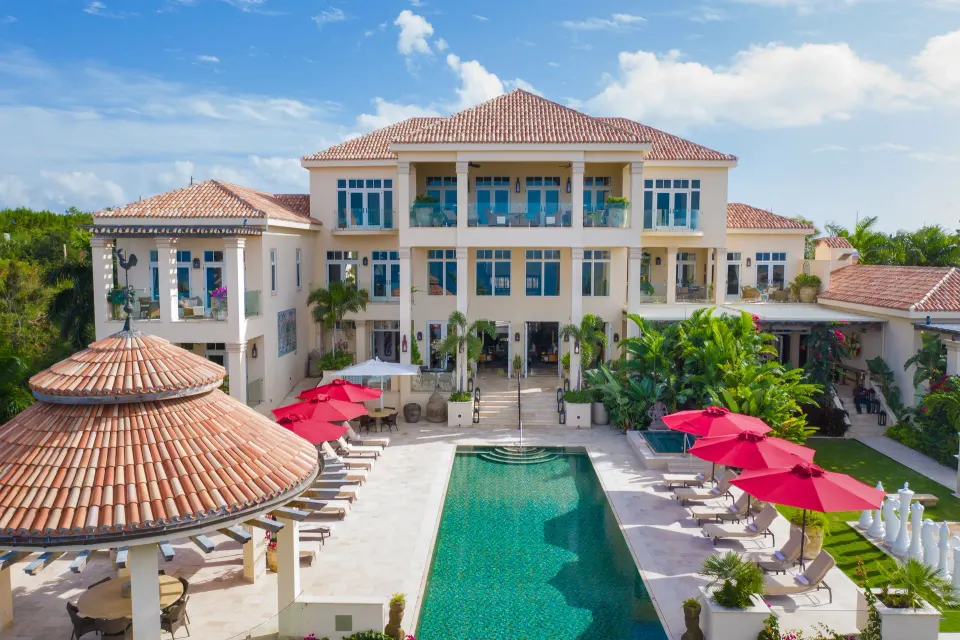 Swimming pool with sun loungers and red umbrellas in front of the resort at Quintessence Hotel