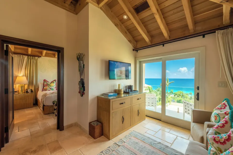 Small living area with sliding doors to ocean and adjacent bedroom at Quintessence Hotel