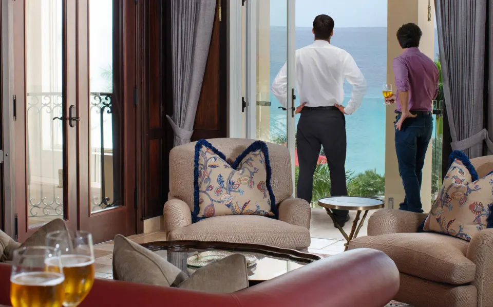 Suite sitting area with terrace and two guests looking toward the ocean at Quintessence Hotel