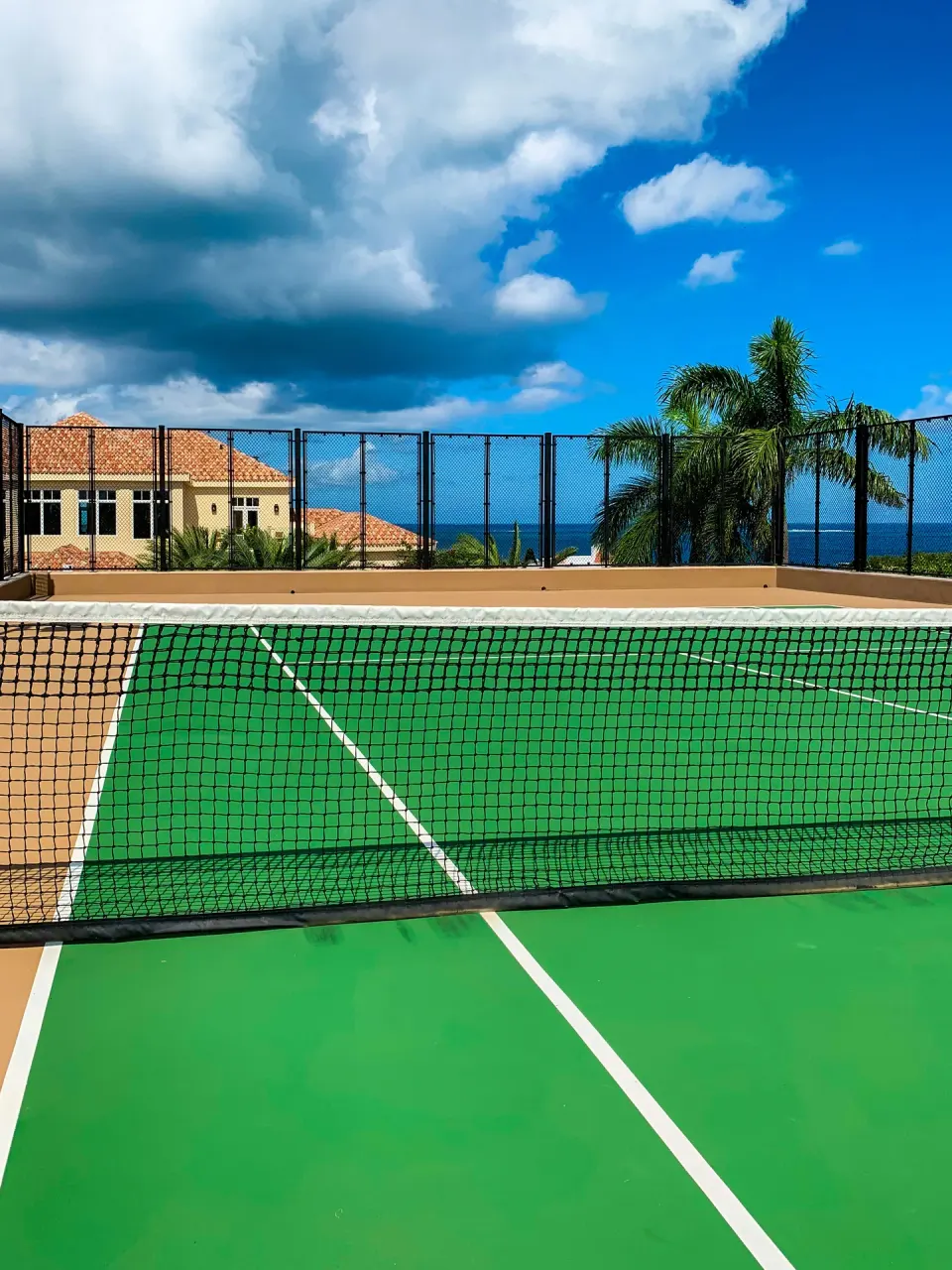 Tennis court with ocean glimpses beyond at Quintessence Hotel.