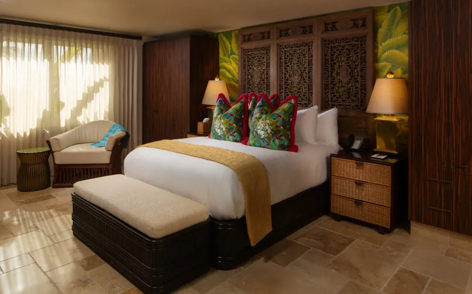 Bedroom with patterned pillows, bedside lamps and a seating corner at Quintessence Hotel