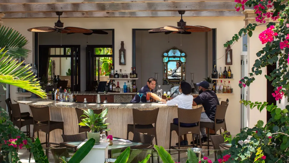 Open-air resort bar with guests seated at the counter at Quintessence Hotel