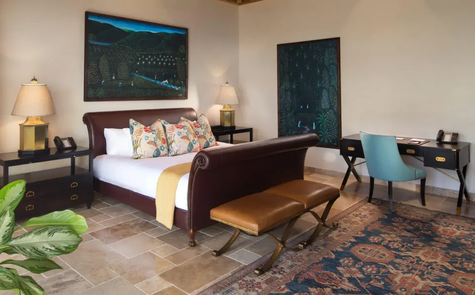 Sleigh-style king bed with desk and patterned rug in suite at Quintessence Hotel