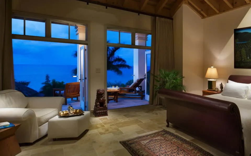 Evening view from suite showing seating, king bed and terrace overlooking the ocean at Quintessence Hotel