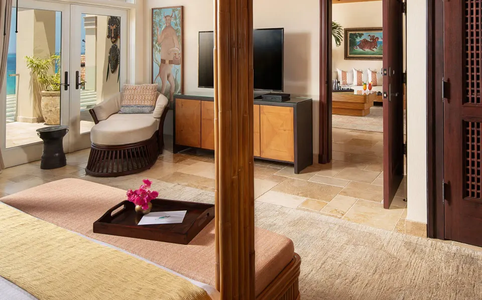 View from foot of bed toward chaise and TV with terrace beyond at Quintessence Hotel